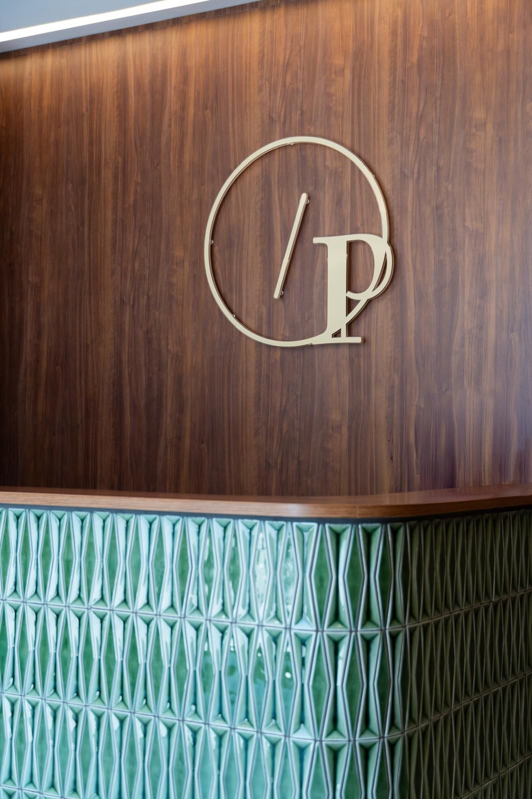 Reception dello Studio Pisano con il logo sulla parete in legno
